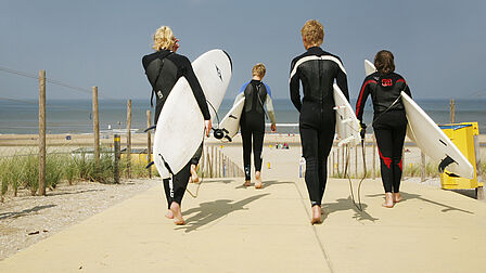 Surfers met surfplank op weg naar de zee