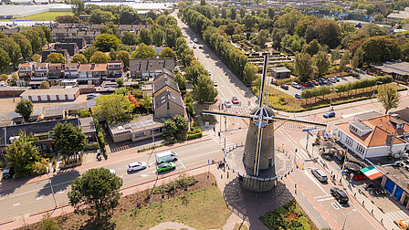 Op de foto is een molen met daaromheen een dorpsgezicht te zien.