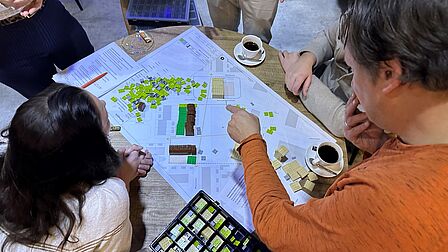 Op de foto zie je een aantal personen in een kring met LEGO aan de slag.