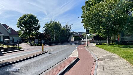 Op de foto zijn autowegen, fietspaden en straatmeubilair te zien. Ook staan meerdere bomen en een lantaarnpaal.