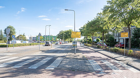 Op de foto is een autoweg en een fietspad te zien. Bij beide wegen staat een gele bord.
