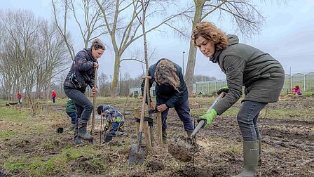 foto van dames die bomen aan het planten zijn.